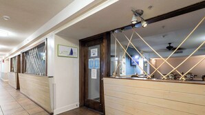 A hotel corridor with wooden paneling, a reception desk with rope decorations, and a sign indicating the use of another door. - Sky-High Oceanfront Stay Pools and DJs & More (Myrtle Beach)