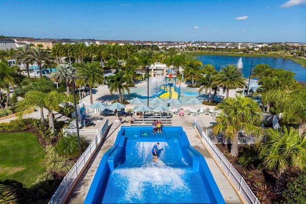 Un parc aquatique doté d’une grande piscine, de toboggans et de palmiers.