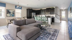 Ein modernes Wohnzimmer mit einem grauen Sofa, einem Glastisch und einem gemusterten Teppich.