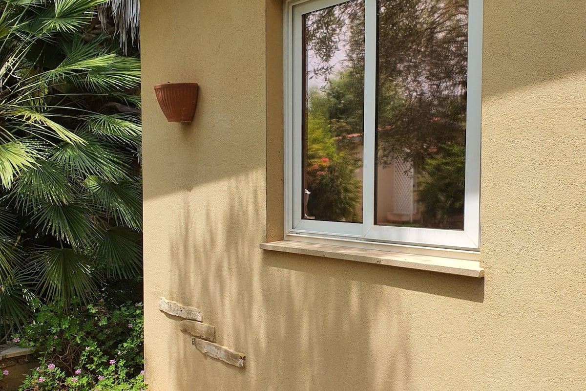 Ein Haus mit einem Fenster, einem Blumentopf und einer gefliesten Terrasse.