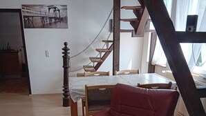 Un coin repas avec une table en bois, des chaises et un escalier.