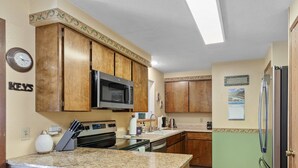 A kitchen with wooden cabinets, a microwave, a stove, and a refrigerator.
