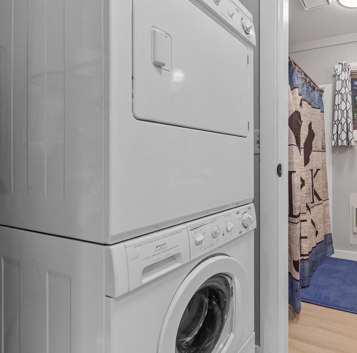 A front-loading washing machine and dryer stacked in a laundry room.