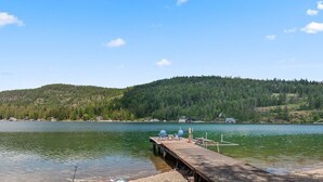 A wooden dock extending into a calm lake with a backdrop of a forested hill.