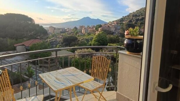 Un balcón con mesa y sillas, con vistas a un pueblo y una montaña.