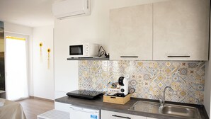 Cocina compacta equipada con microondas, tostadora y lavamanos.