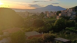Un pueblo costero con edificios, una montaña al fondo y un atardecer.