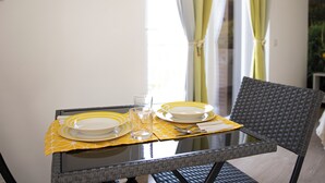 Una mesa de comedor con dos platos, un vaso y cubiertos sobre un mantel individual amarillo.