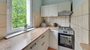 A kitchen with a window, a stove, an oven, and cabinets. - RentPlanet - Apartament Piastowska (Gdansk)