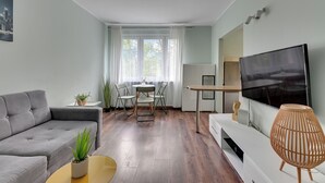 A modern living room with a grey sofa, a small round table, a TV, and a decorative lamp. - RentPlanet - Apartament Piastowska (Gdansk)