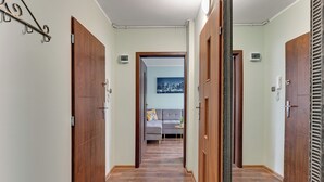 A hallway with wooden doors, a grey sofa, and a cityscape painting on the wall. - RentPlanet - Apartament Piastowska (Gdansk)