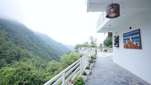 Un balcon doté d’une balustrade blanche, donnant sur une vallée verdoyante.