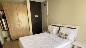 Een keurig opgemaakt slaapkamer met een bed, nachtkastje en een kledingkast.