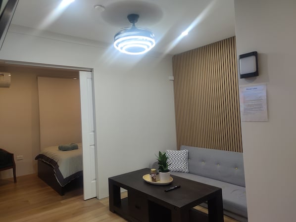 A modern living room with a sofa, a coffee table, and a ceiling light fixture.