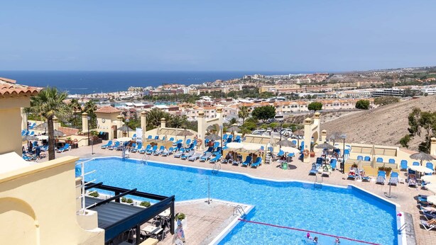 A pool area with sun loungers and a view of the sea. - Andalucia 5 - One Bed (Costa Adeje)