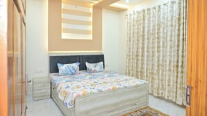 Un dormitorio con cama, mesitas de noche, ventilador de techo y ventana con cortinas.