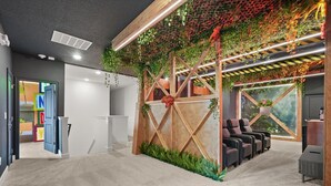 Een receptiegedeelte met een houten scheidingswand, zitplaatsen en een wand met hangplanten.