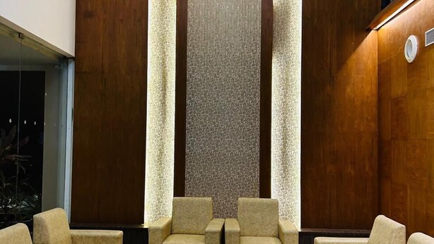 A lobby with a wooden wall, a central column, and seating arrangements. - Monarch Express, Sri City (Tada)