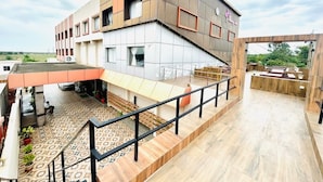 A modern building with a flat roof, a covered outdoor area with a patterned floor, and a staircase leading to an upper level. - Monarch Express, Sri City (Tada)