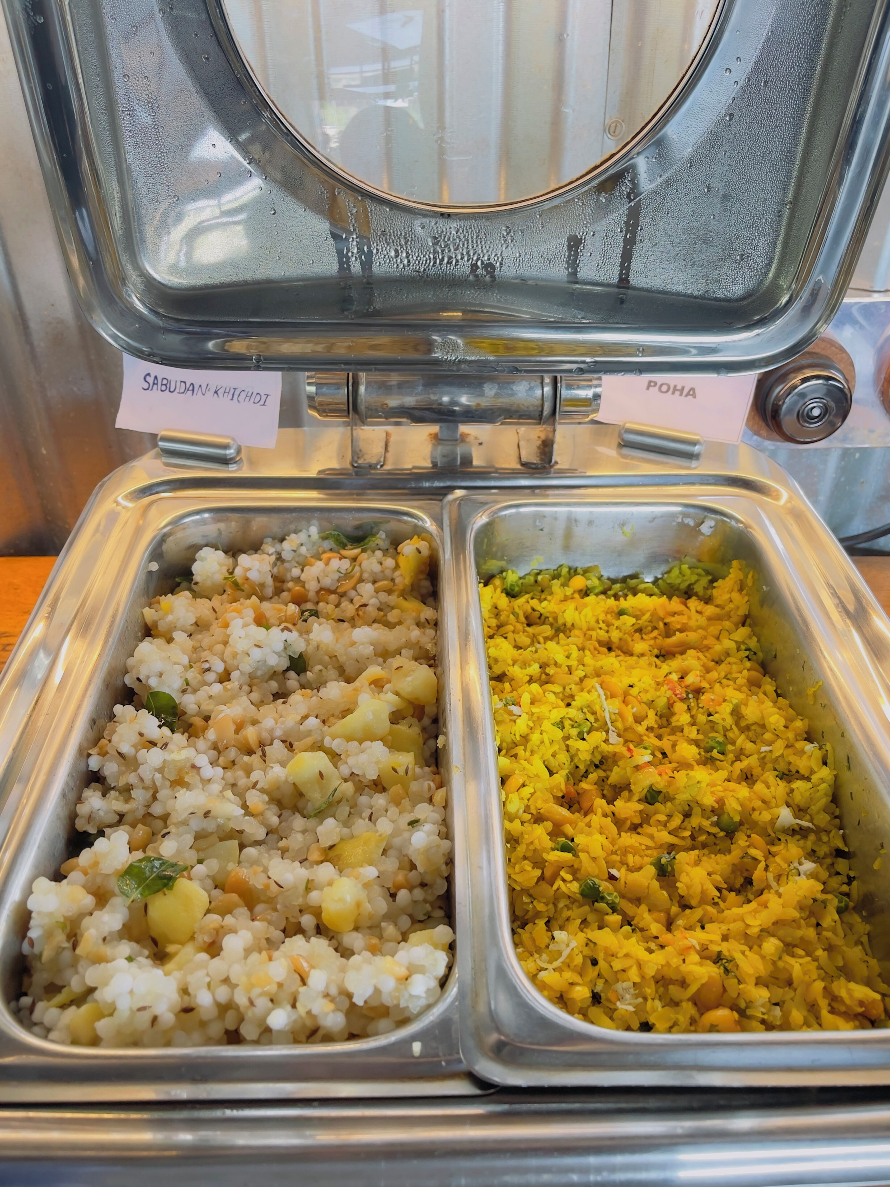 Un buffet divisé en deux sections, chacune étant clairement identifiée : une section pour le sabudan khichdi et une autre pour le poha.