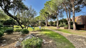 A park with playground equipment, trees, and a stone pathway. - Casa Sunrise by Wonderful Italy (Olbia)