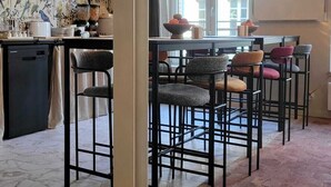 A dining area with hexagonal patterned flooring, a bar with stools, and a wall with a bird-themed wallpaper. - 4 Charming Suites & downtown (Sens)