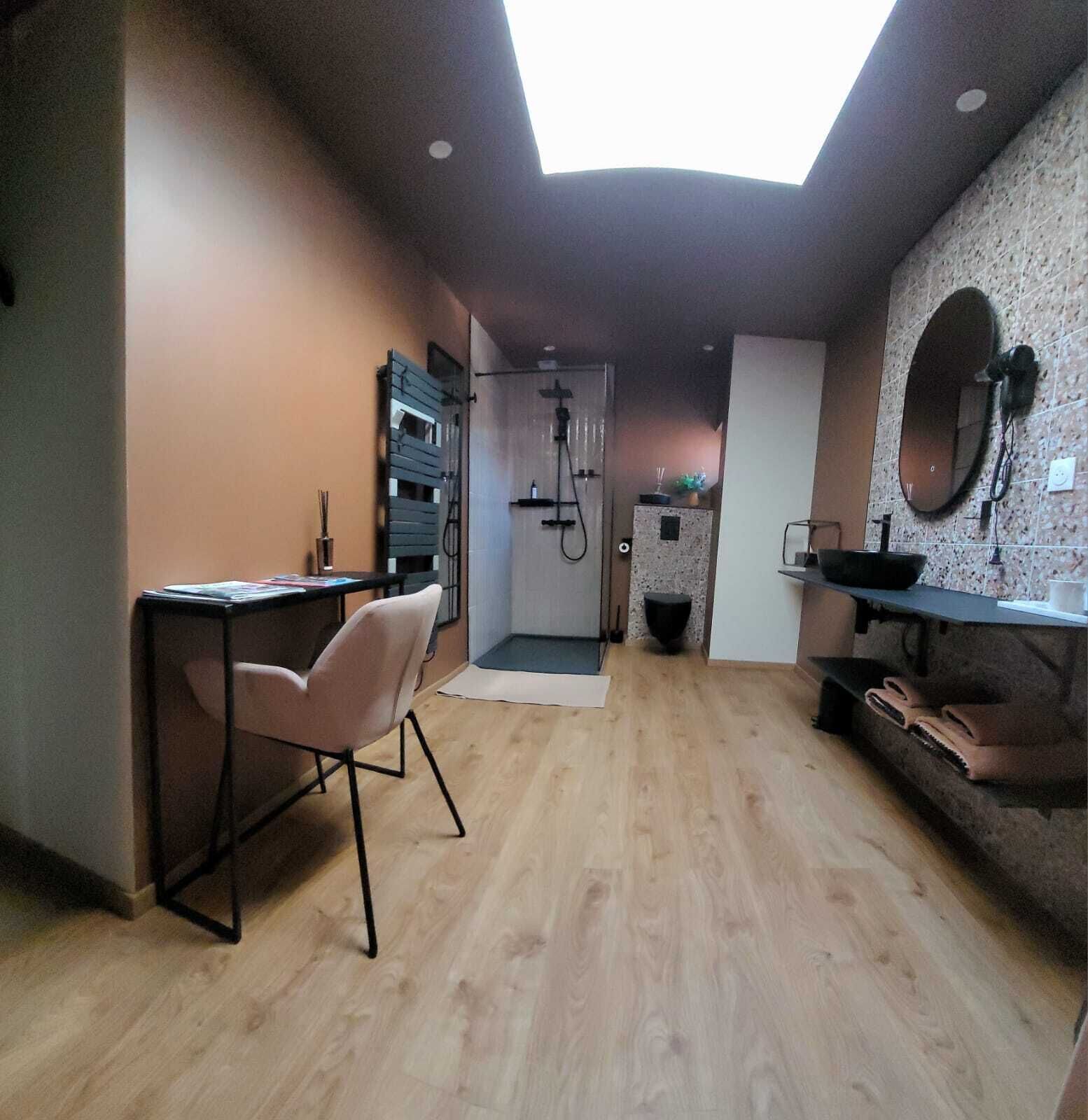Une cuisine moderne dotée d’une verrière, d’un plancher en bois et d’un coin repas avec une chaise et une table.