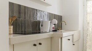 Een keuken met een wit aanrecht, een spoelbak en een achterwand van grijze tegels.