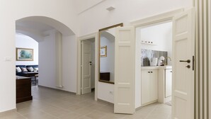 Een ruime hal met een open deur naar een badkamer, een zithoek met een bank en een keuken met kasten en een aanrecht.