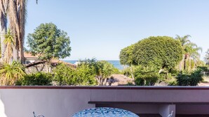 A terrace with a round table and chairs, overlooking a beach and palm trees. - Margiù Capomulini Home by Wonderful Italy (Acireale)