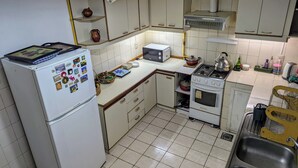 Eine kompakte Küche mit Kühlschrank, Herd, Mikrowelle und Spüle.
