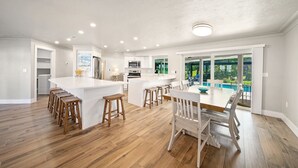 Une cuisine spacieuse dotée d’un grand îlot central, de tabourets de bar en bois et d’une table à manger avec des chaises.