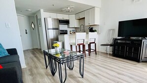 A modern kitchen with white cabinets, a stainless steel refrigerator, and a black countertop.