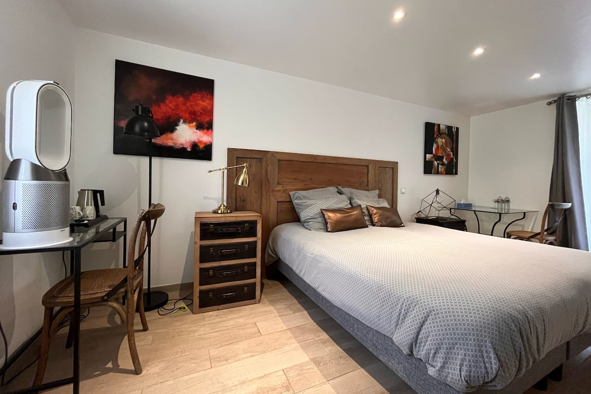 A modern bedroom with a wooden headboard, a large bed, a desk with a computer, and a chair.