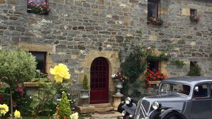 A stone building with a red door, flower boxes, and a vintage car parked in front. - Auberge de keranden (Landerneau)