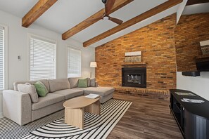 A living room with a brick fireplace, a sofa, a coffee table, and a television.