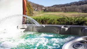 Un bain à remous avec vue sur un paysage verdoyant et des collines en arrière-plan.