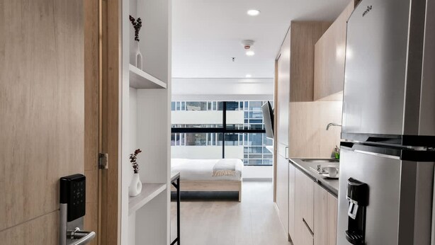 A modern kitchen with a built-in refrigerator, a coffee machine, and a bed in the background. - NOK Spectacular Loft in Usaqu n (Bogotá)