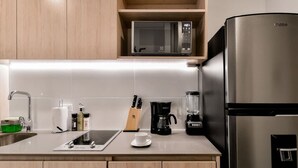 A modern kitchen with a stainless steel refrigerator, a microwave, a coffee maker, and a knife block.