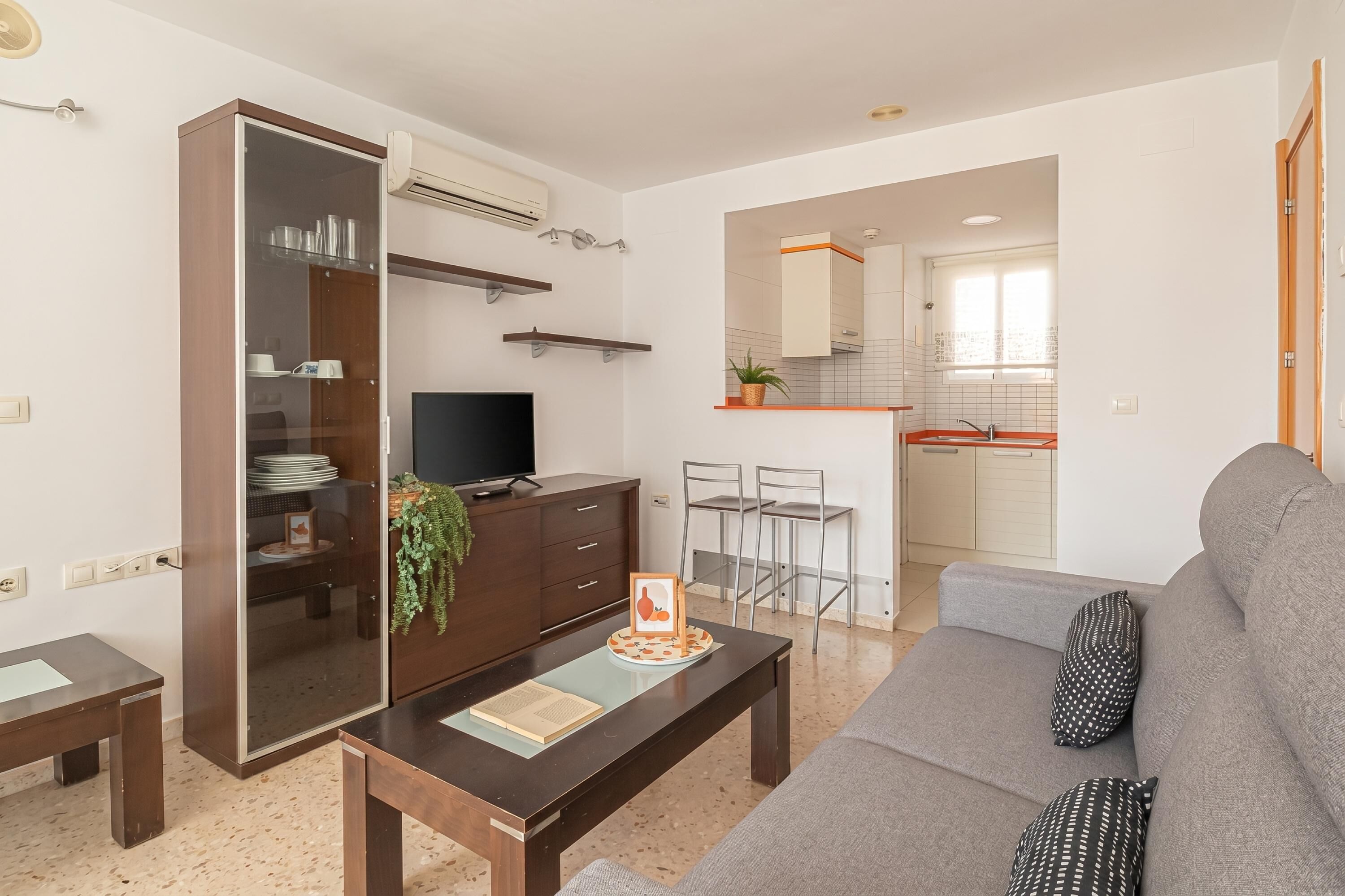 Una sala moderna con un sofá, una mesa de centro, un televisor y un armario con puerta corredera.