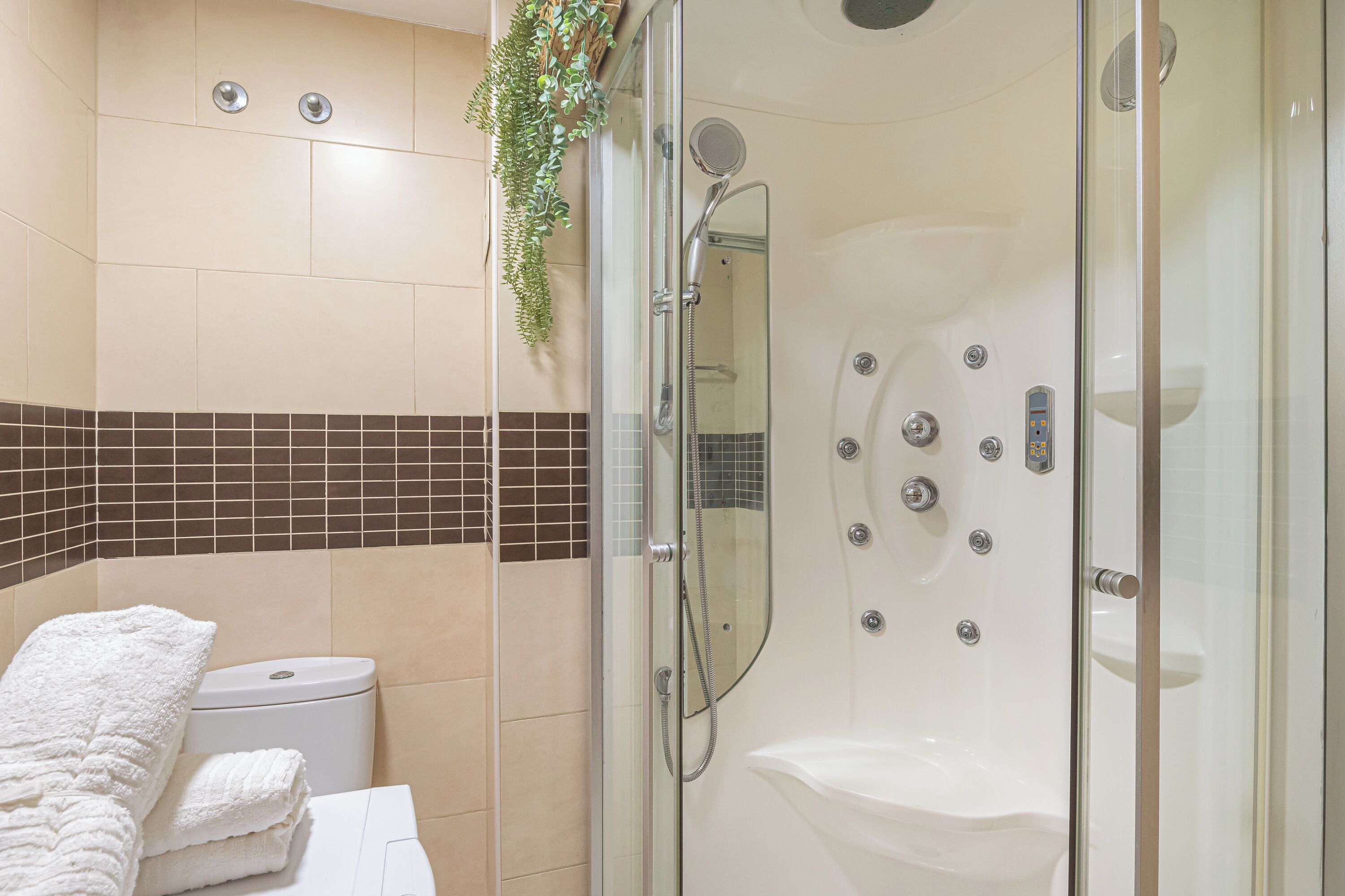 Une salle de bain moderne dotée d’une douche à parois de verre, de toilettes et d’un lavabo.