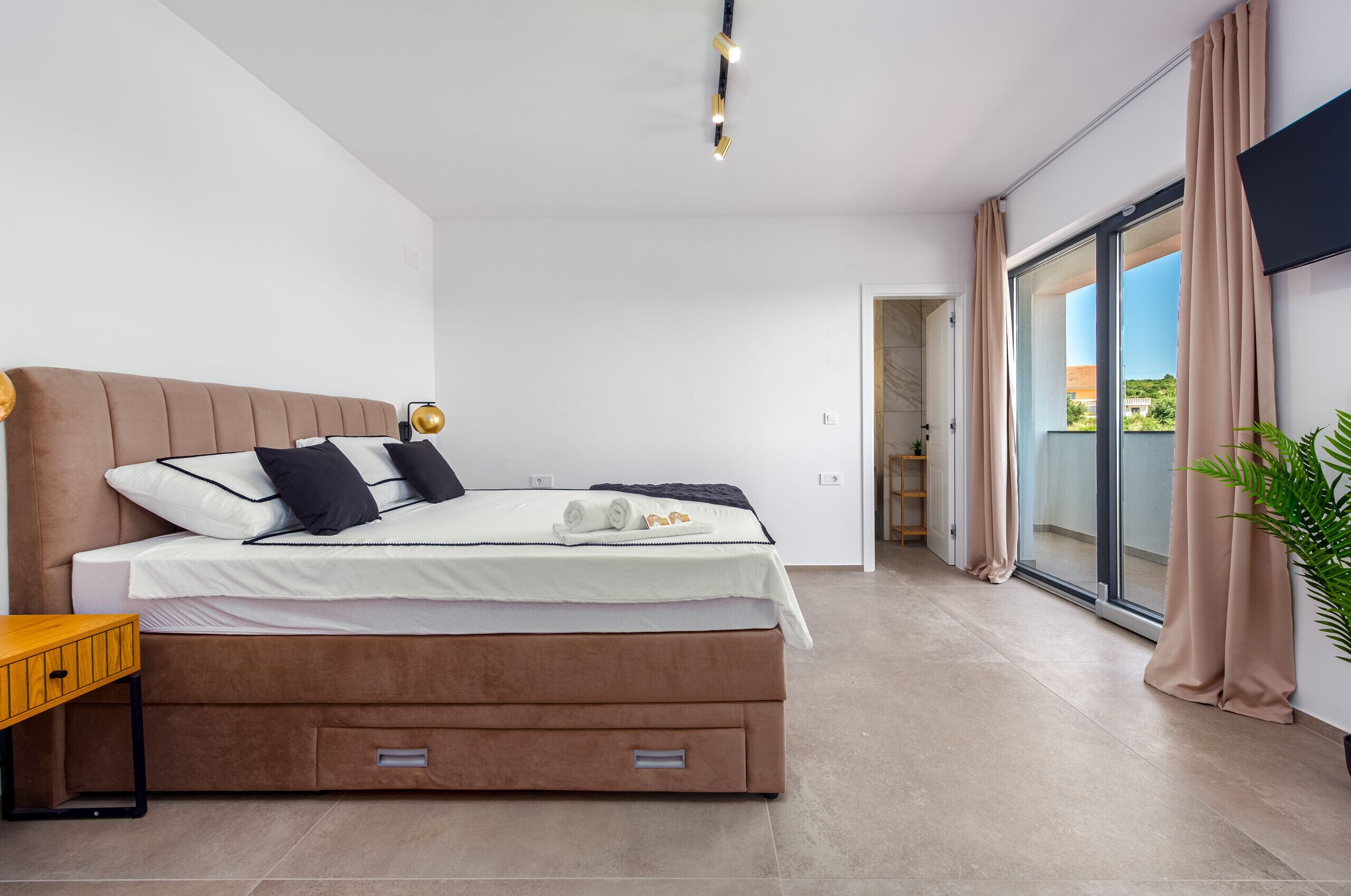 Un dormitorio moderno con una cama grande, puertas corredizas de vidrio a un balcón y una decoración minimalista.