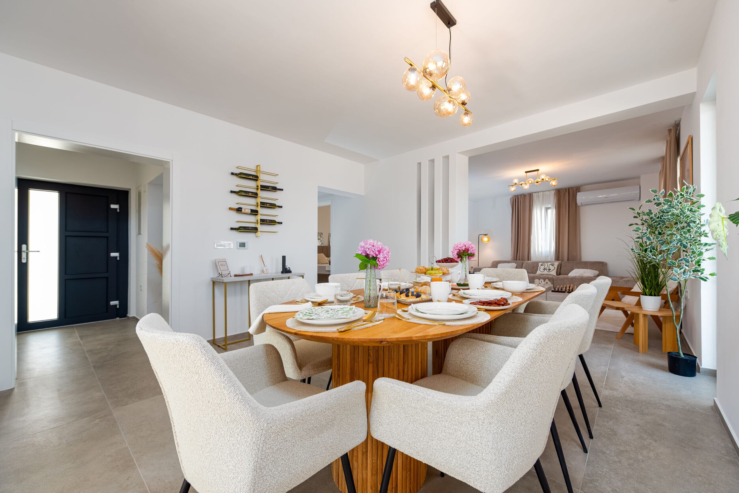 Un comedor moderno con una mesa redonda de madera, sillas blancas tapizadas y una araña.