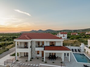 A modern two-story house with a red-tiled roof, a swimming pool, and a view of the surrounding landscape. - Villa di Lago Zadarvillas (Pakostane)