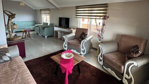 A spacious living area with a sofa, armchairs, a coffee table, and a television. - Has Home Nozbart (Trabzon)