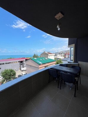 Balcón con mesa y sillas, vistas a una zona residencial y al mar.