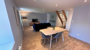 Una sala moderna con una mesa de comedor de madera, un sofá azul y una escalera.