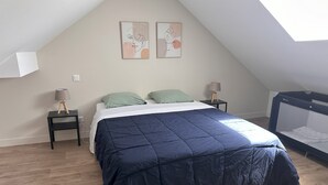 Un dormitorio con cama, dos mesitas de noche, un colchón en el suelo y un tragaluz.