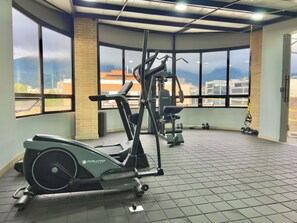 Ein Fitnessstudio mit Rudergerät, Hantelbank und Kurzhanteln.