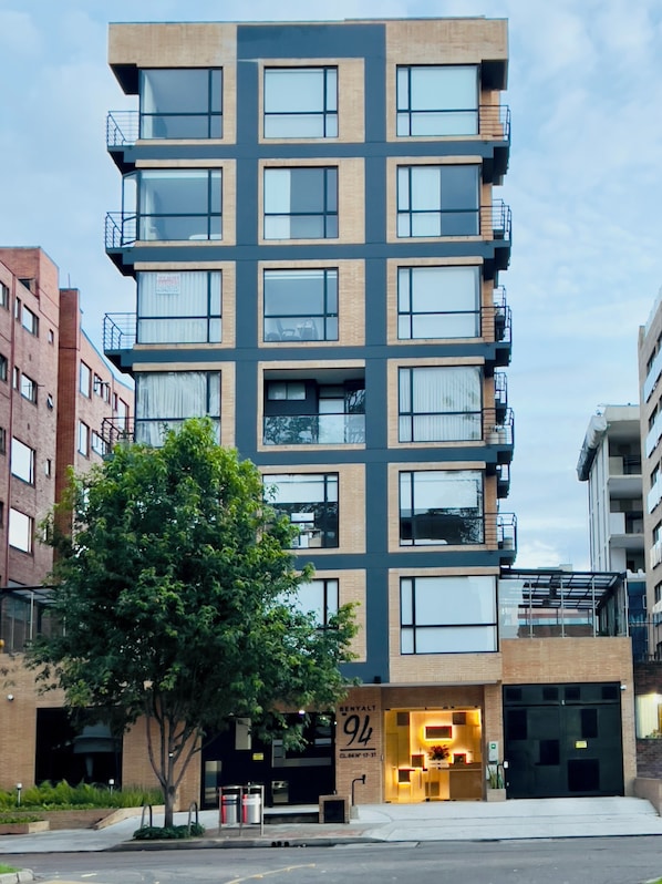 Ein mehrstöckiges Gebäude mit modernem Design, mit Balkonen und großen Fenstern.